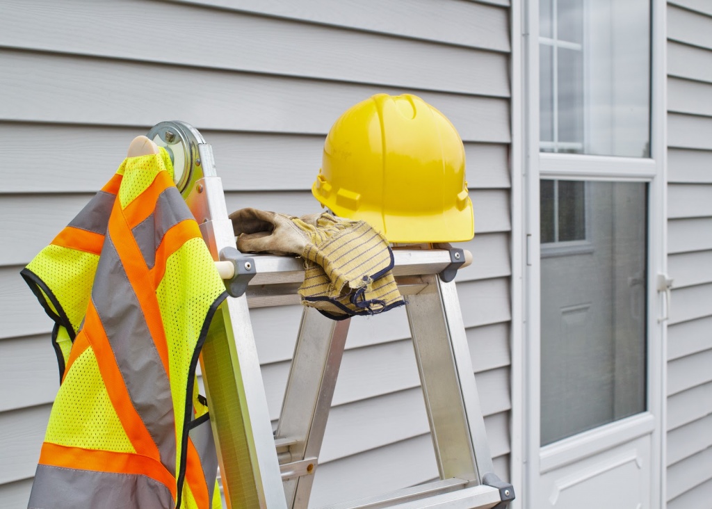 vinyl siding contractor ladder with protectice construction gear on the side of a house